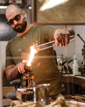 Man working with glassblowing tools in a workshop